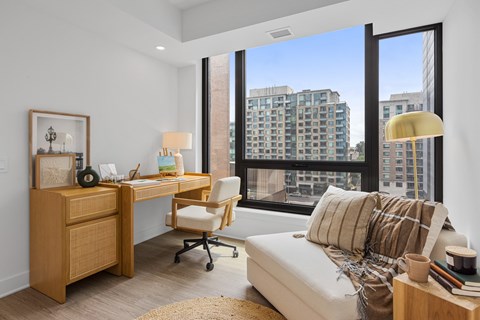 a bedroom with a large window and a desk with a chair and a couch